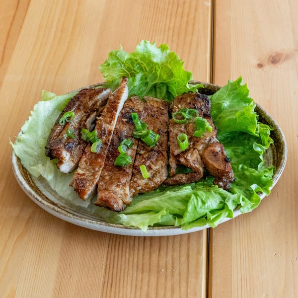 Grilled pork chops, sliced and topped with green onions, served on a bed of lettuce.